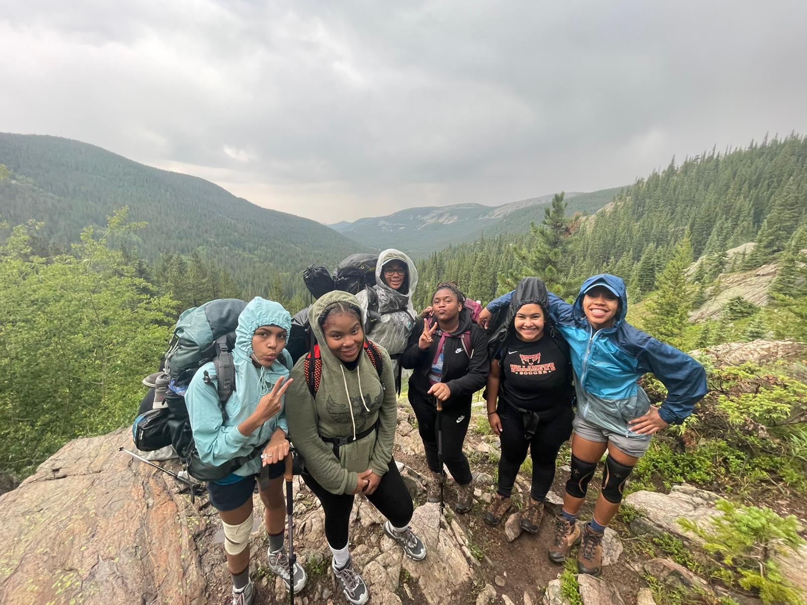 A group of people look up at a camera with backpacks on